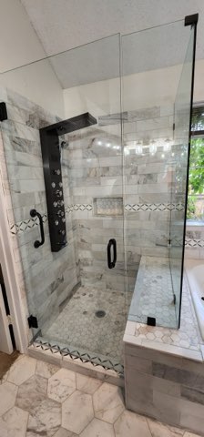 Marble shower with frameless glass enclosure and body jets