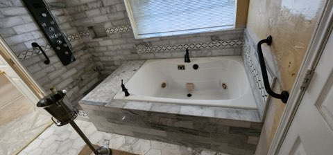 Jetted soaking tub with marble tile surround