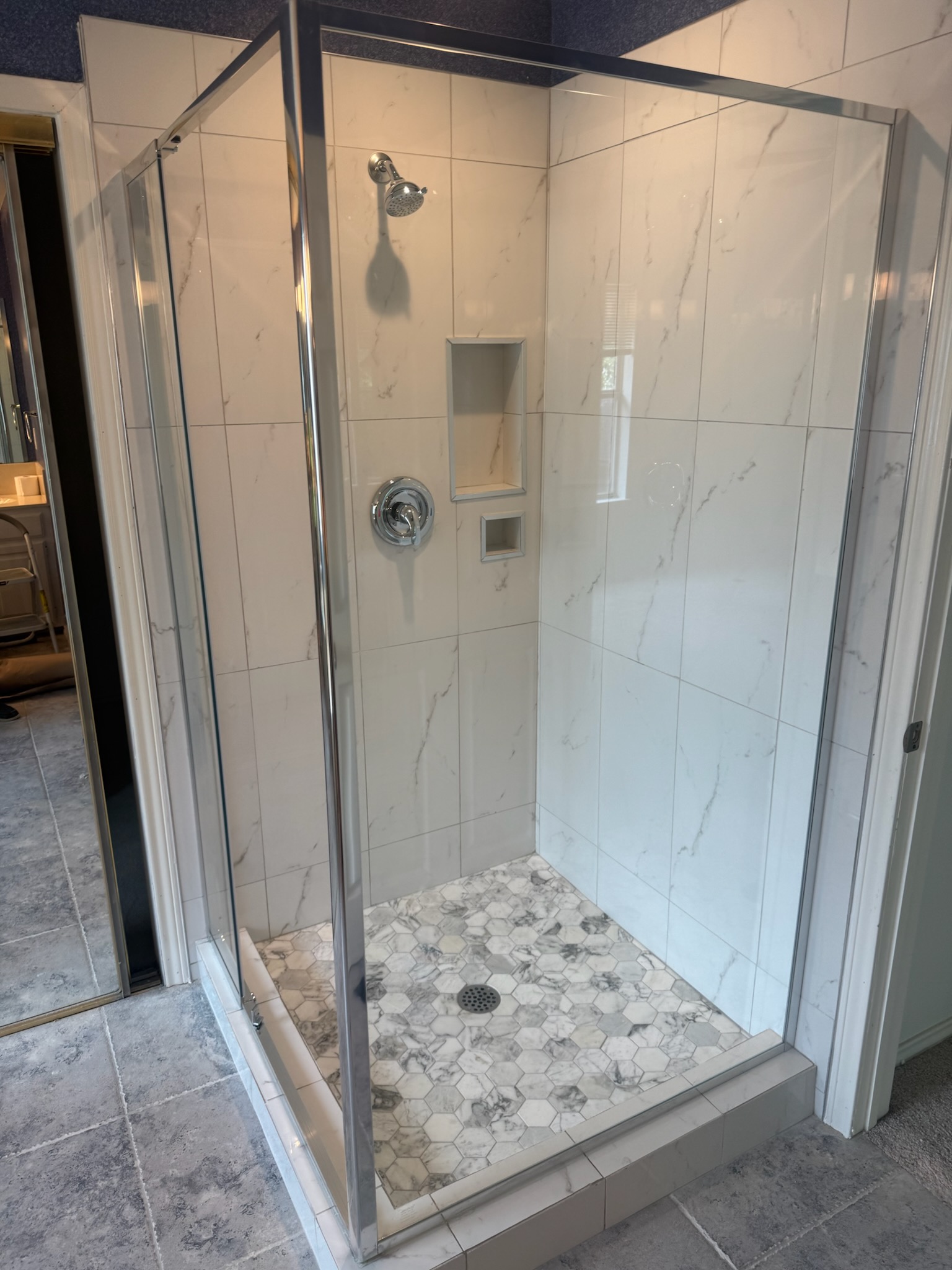 Completed shower remodel with marble tile and built-in niche