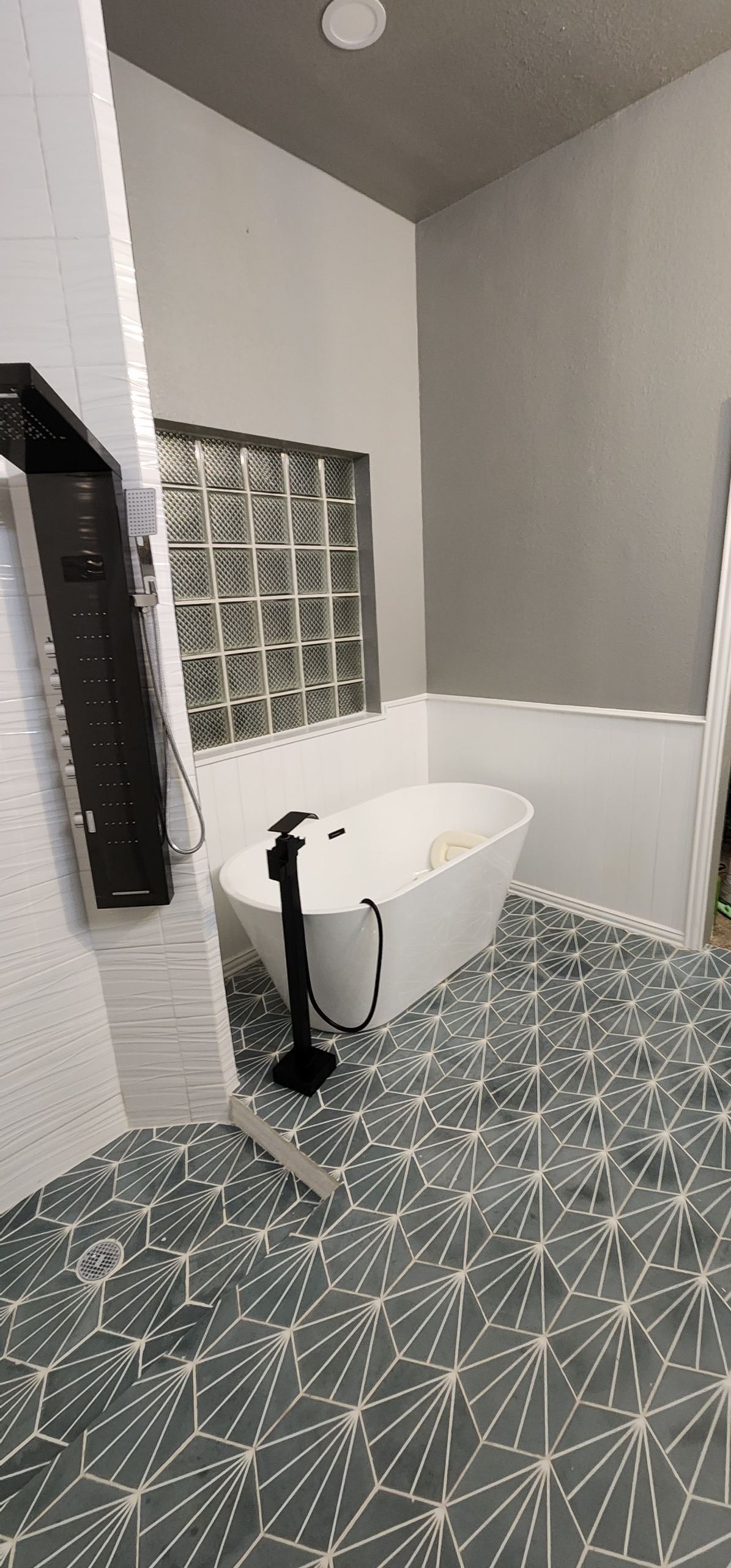 Freestanding white soaking tub with black floor-mount filler