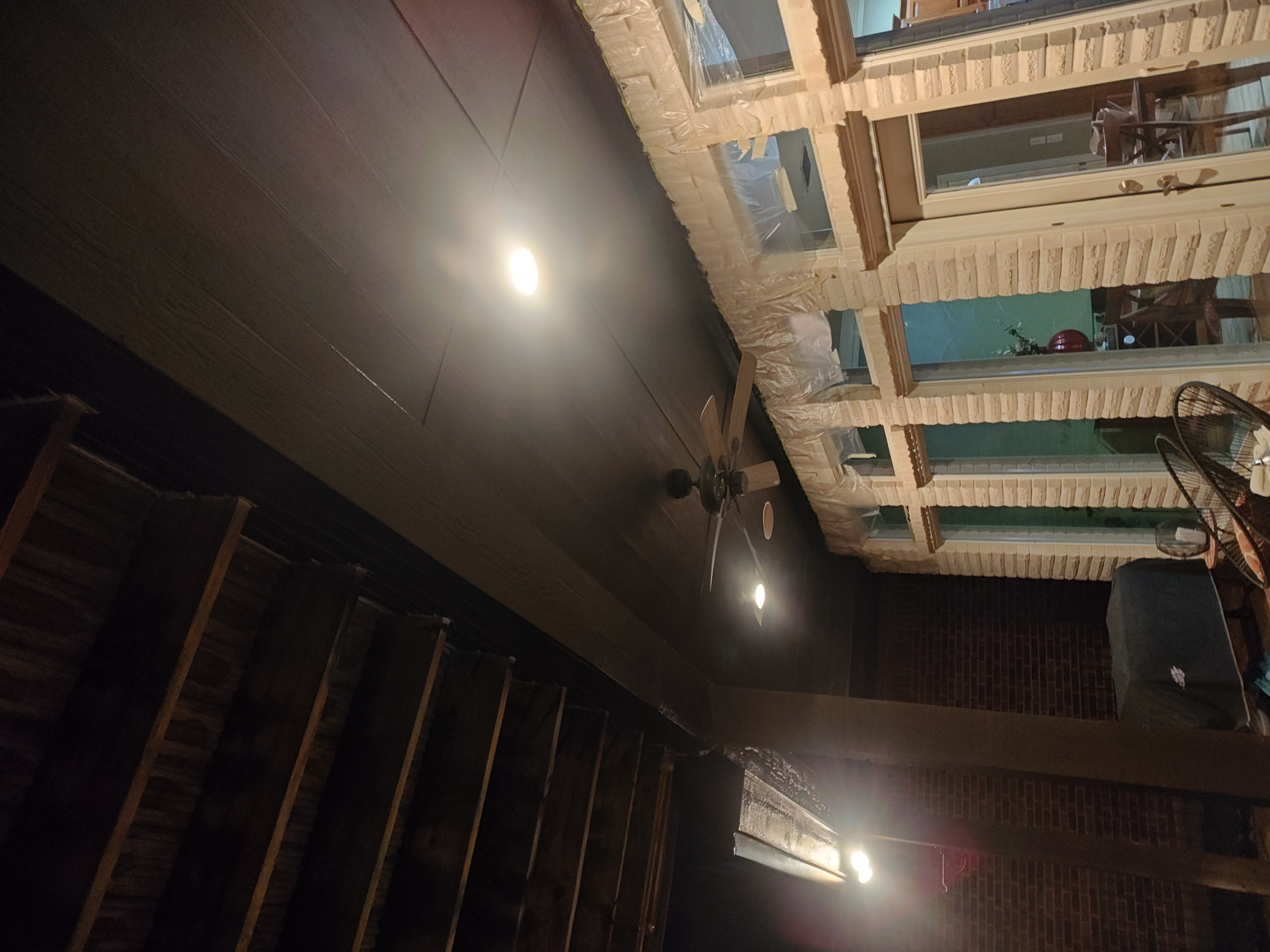 Patio ceiling painted black with recessed lighting and ceiling fan